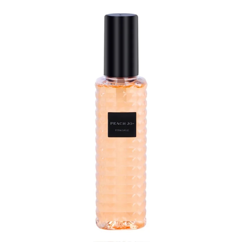 Perfume bottle with peach-colored liquid and black cap on a white background