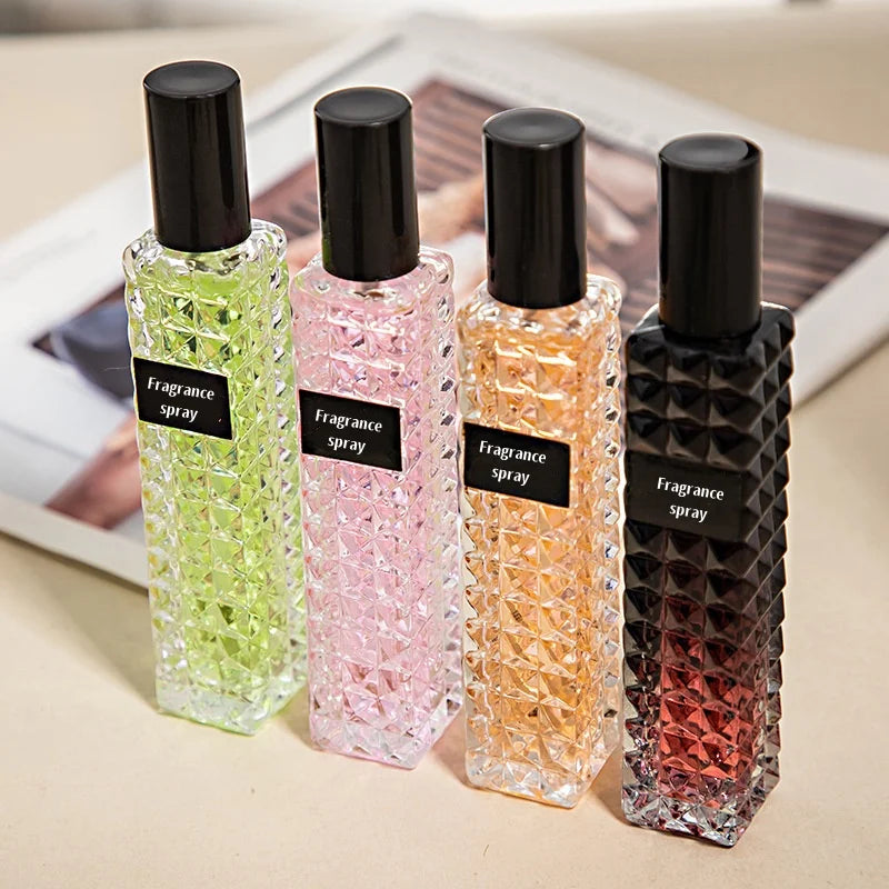 Four fragrance spray bottles with different colored liquids on a light surface.